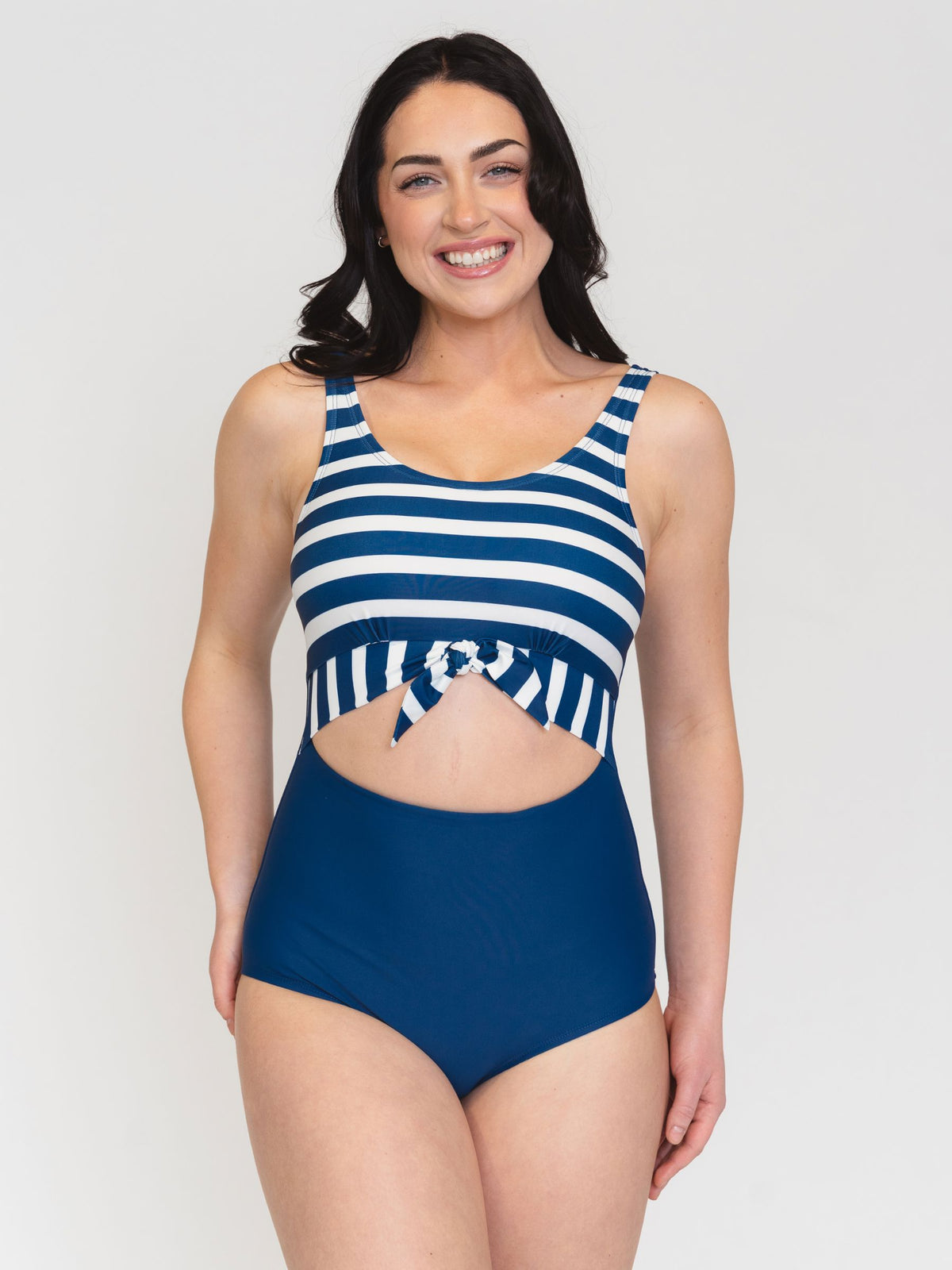 Woman wearing a blue and white striped swimsuit on a plain background