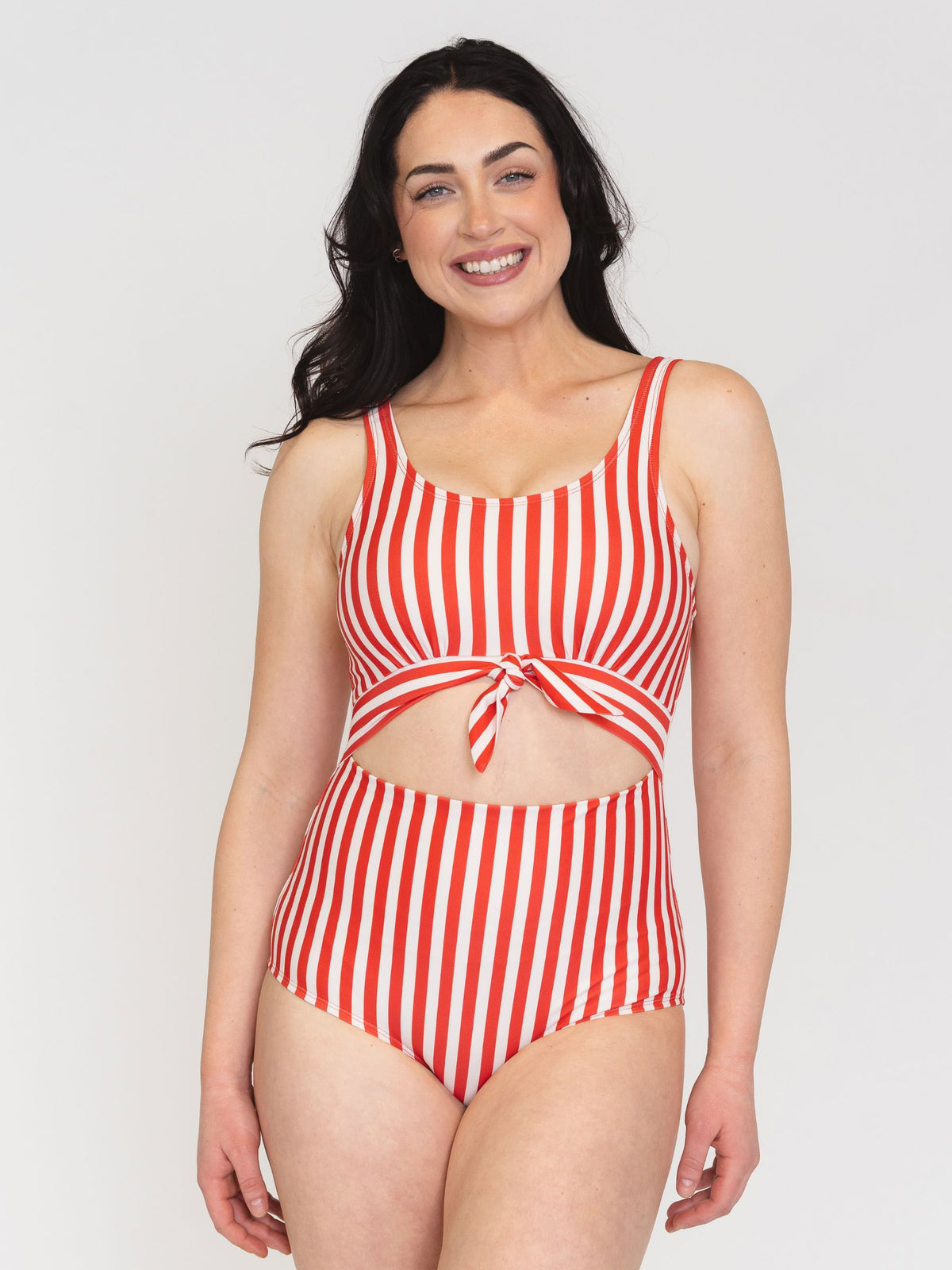 Woman wearing a red and white striped swimsuit on a plain background