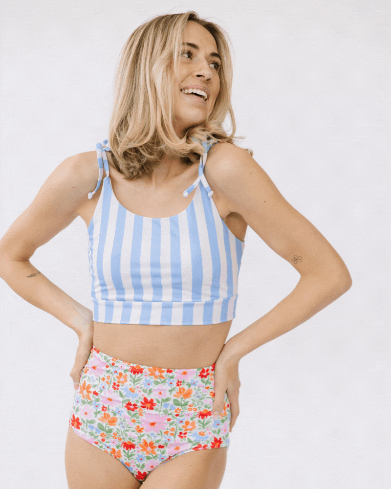 GIF of a woman wearing a peri stripe shoulder-tie swim crop top and a floral swim bottom