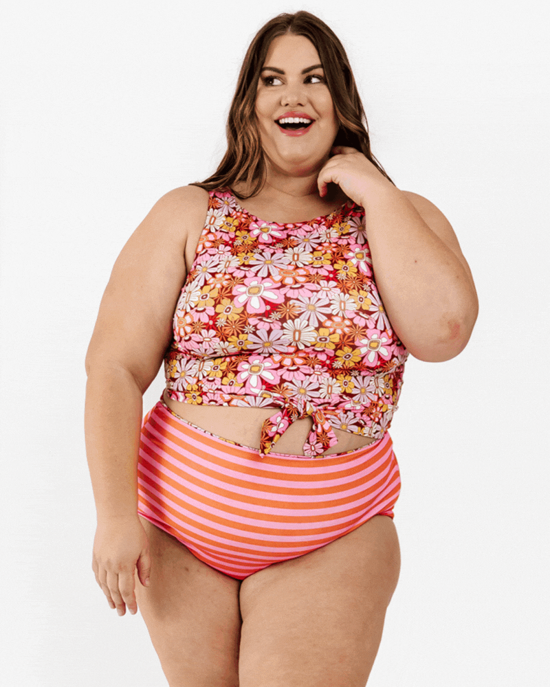 GIF of a woman wearing a Groovy Blooms floral knotted swim crop top and an orange and pink stripe swim bottom
