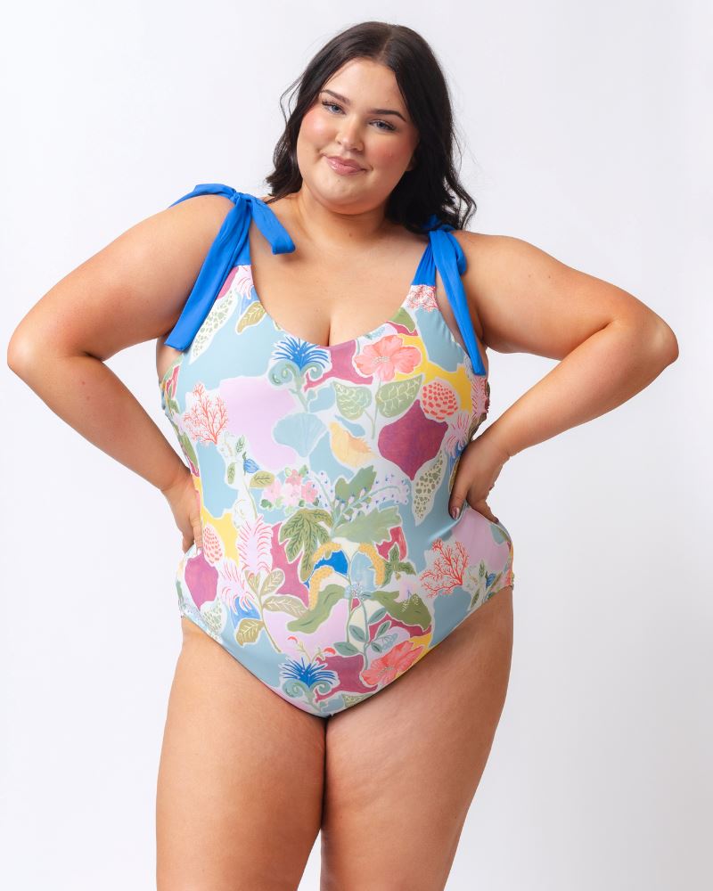 Photo of a woman wearing a colorful seashell inspired shoulder-tie one-piece swim suit