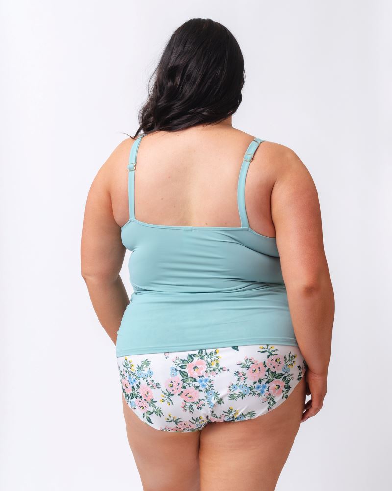 Photo of a woman wearing a light blue square neck swim tankini top and a white and pink floral swim bottom- back angle