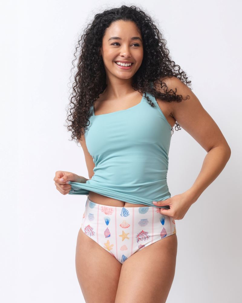 Photo of a woman wearing a seashell striped high waist swim bottom and a slight blue square neck swim tankini top