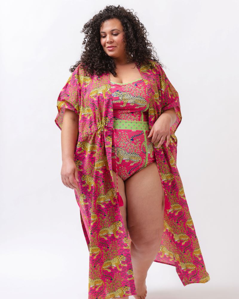 Photo of a woman wearing a bold pink and green print featuring tigers classic one-piece swim suit and a bold pink print featuring tigers swim suit cover-up