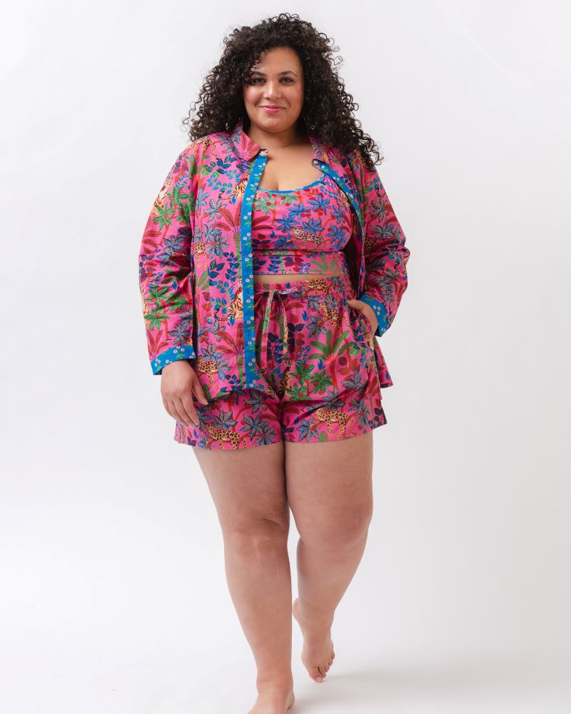 Photo of a woman wearing a bold pink and blue print featuring tigers and leopards shoulder-tie swim crop top and a bold pink and blue print featuring tigers and leopards button down two-piece swim suit cover-up
