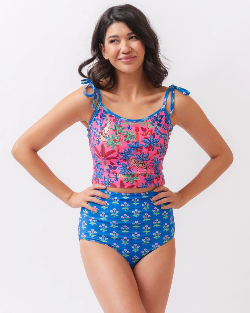 Photo of a woman wearing a bold pink print featuring tigers/ blue and pink floral reversible ultra high waist swim bottoms- floral side and a bold pink print featuring tigers shoulder-tie swim crop top