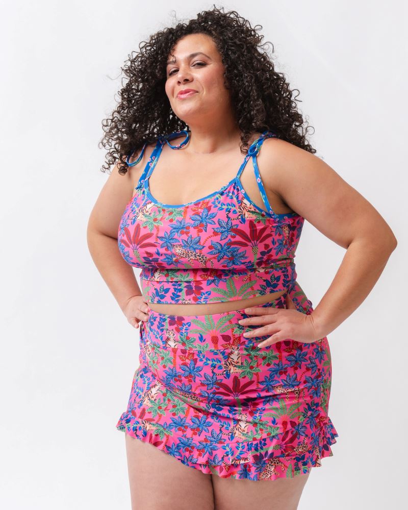 Photo of a woman wearing a bold pink and blue print featuring tigers and leopards shoulder-tie swim crop top and a bold pink print featuring tigers and leopards swim skirt