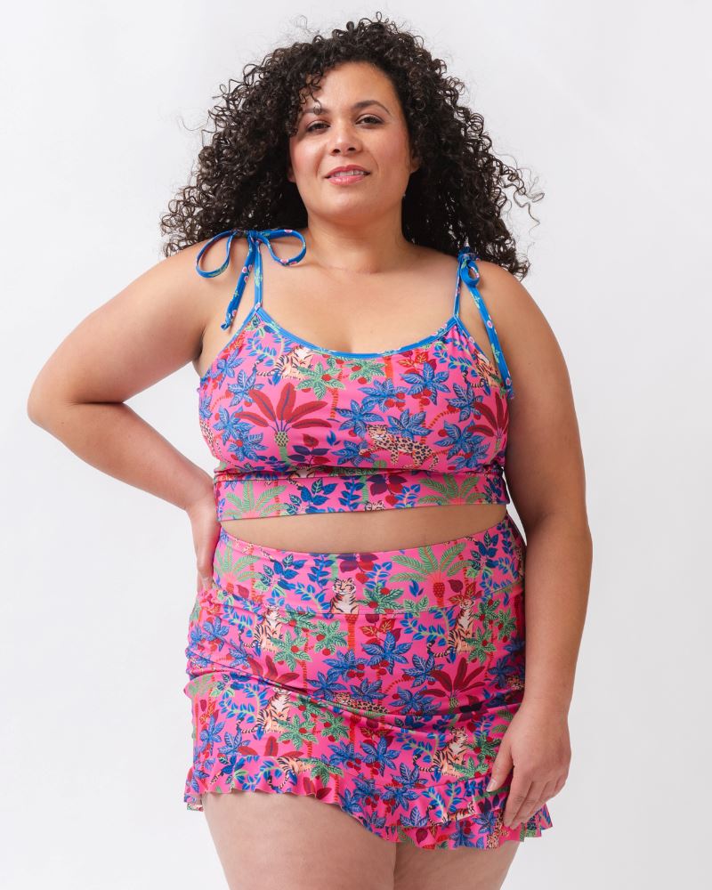 Photo of a woman wearing a bold pink and blue print featuring tigers and leopards swim skirt and a bold pink and blue print featuring tigers and leopards shoulder-tie swim crop top