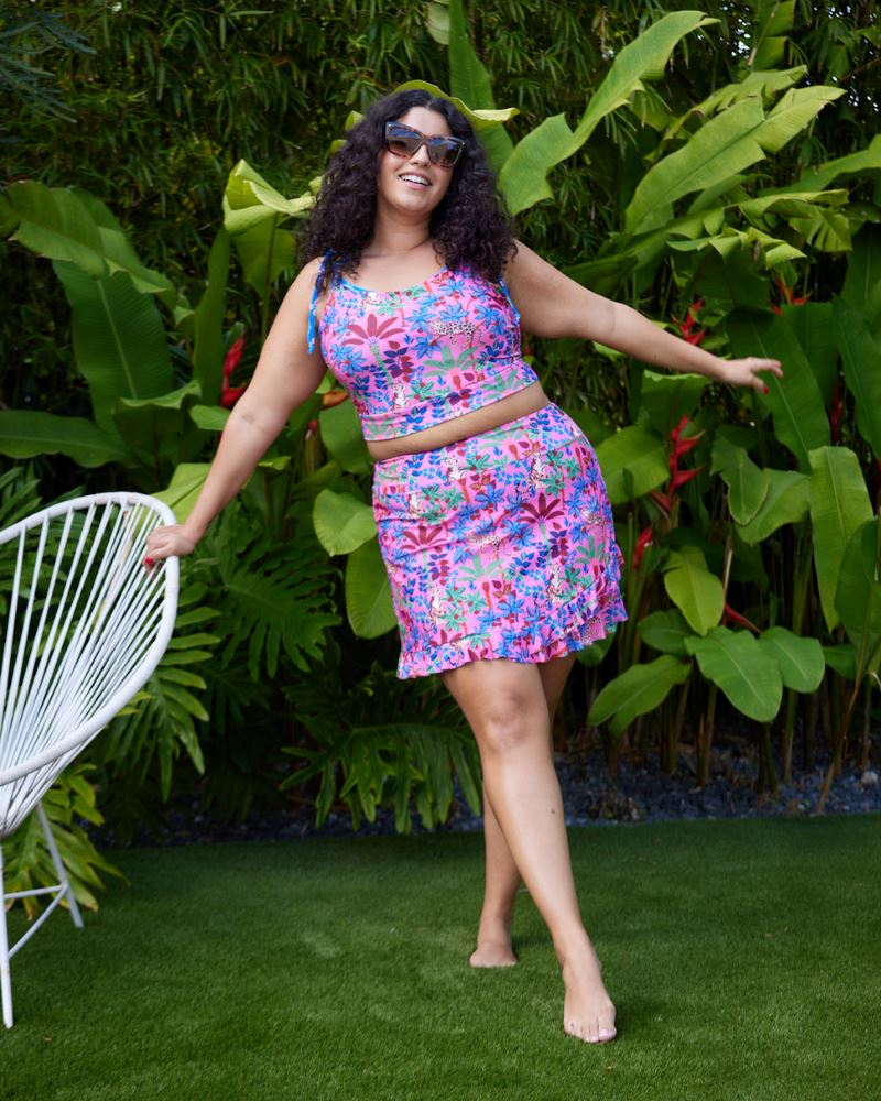 Photo of a woman wearing a bold pink and blue print featuring tigers and leopards shoulder-tie swim crop top and a bold pink and blue print featuring tigers and leopards swim skirt