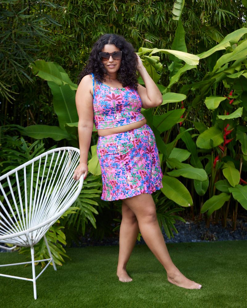 Photo of a woman wearing a bold pink and blue print featuring tigers and leopards swim skirt and a bold pink and blue print featuring tigers and leopards shoulder-tie swim crop top