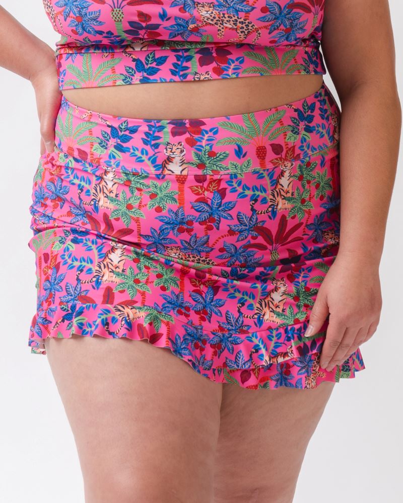Close-up photo of a woman wearing a bold pink and blue print featuring tigers and leopards swim skirt