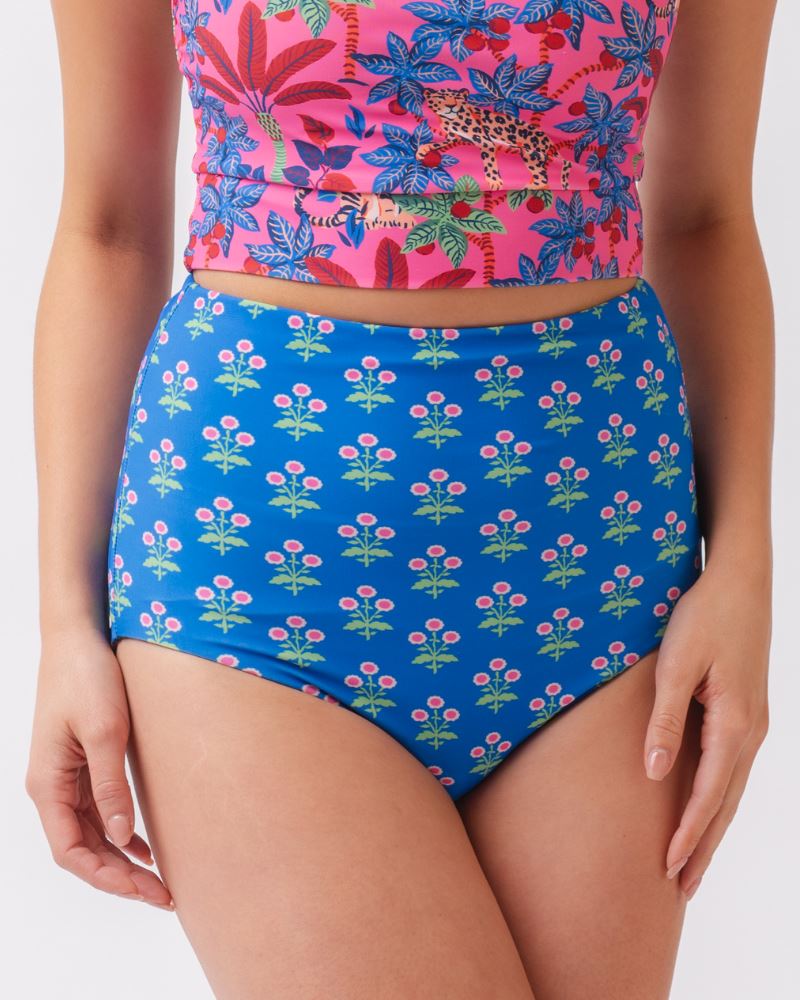 Close up photo of a woman wearing a bold pink print featuring tigers/ blue and pink floral reversible ultra high waist swim bottoms- floral side