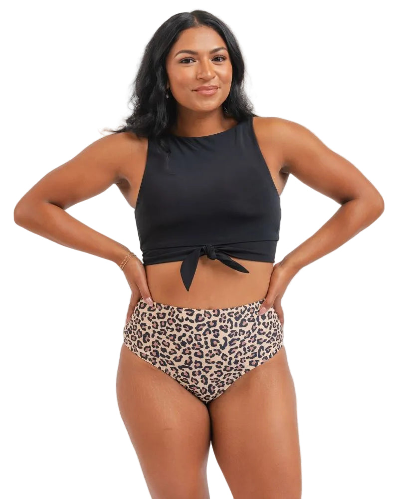 A woman modeling a two-piece swimsuit with a black halter crop top and high-waisted leopard print bikini bottoms, posed against a white background.