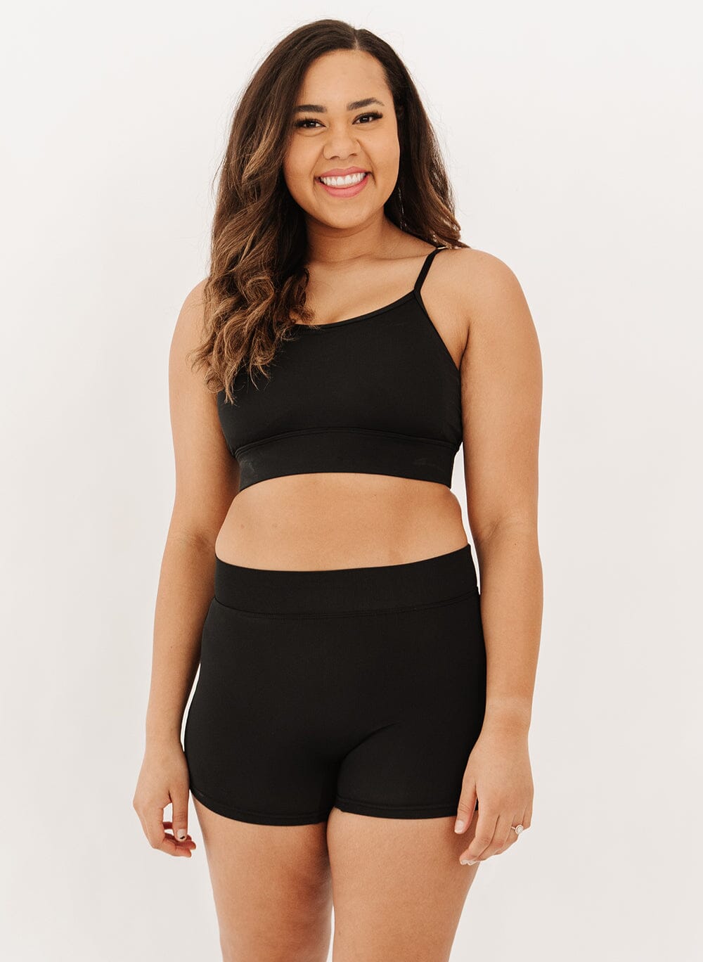 Woman wearing a black swim bralette and black swim shorts