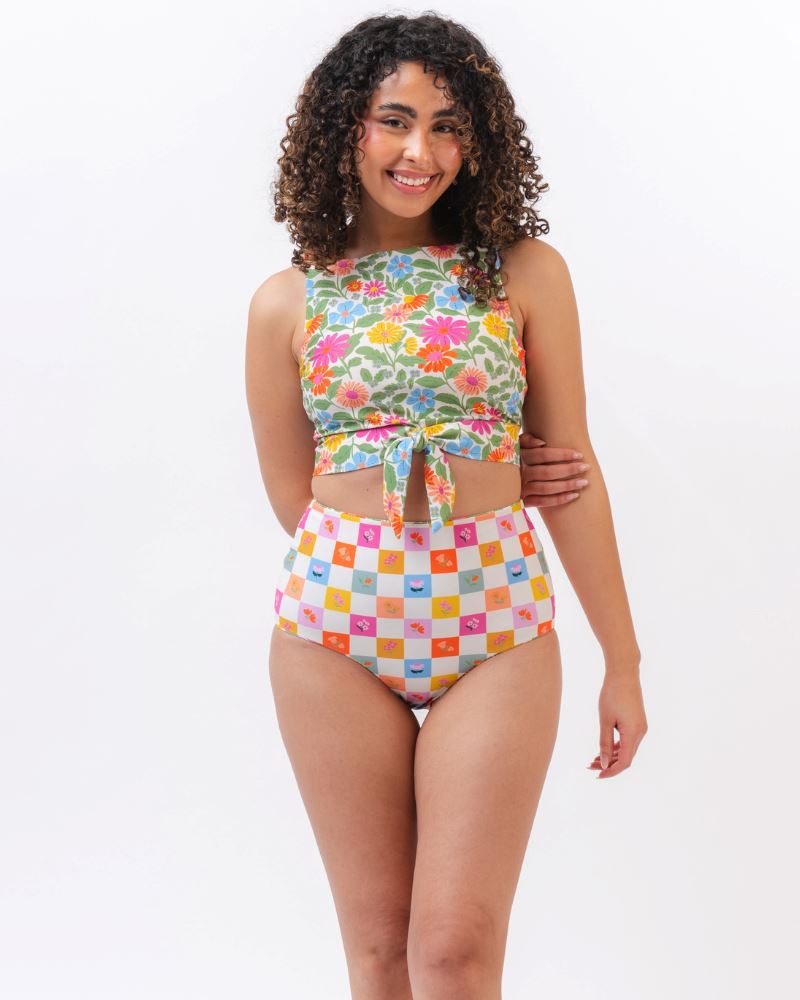 Photo of a woman wearing a multi colored floral cropped swim top with multi colored checkered high waist swim bottoms