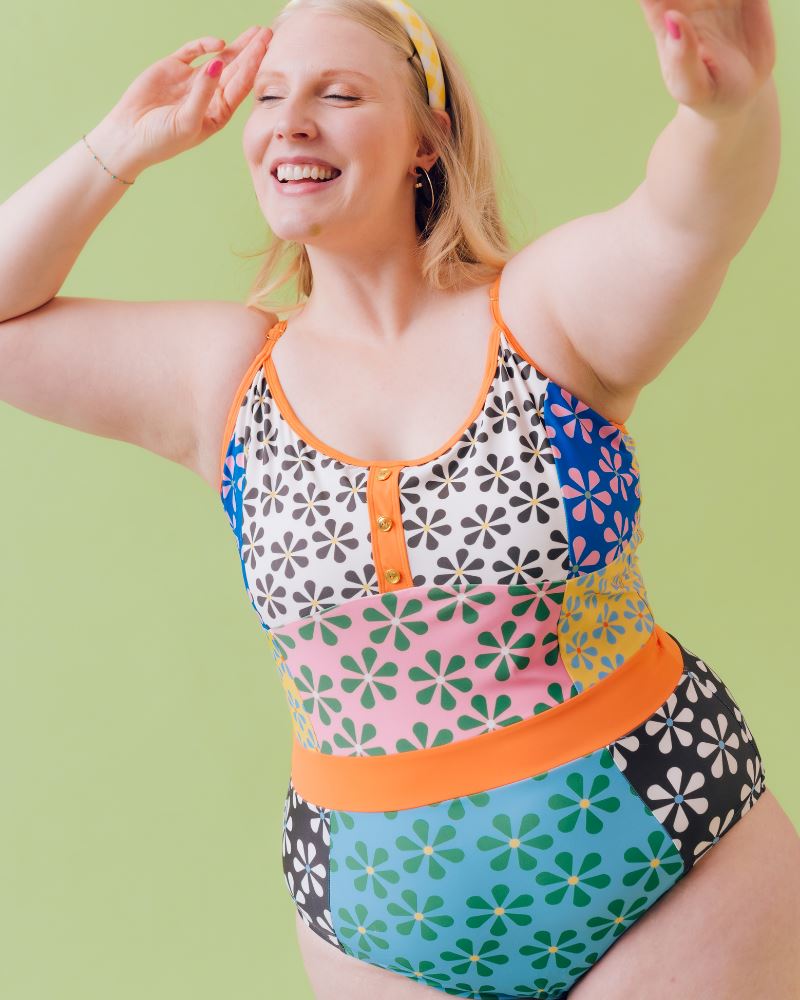 Close-up photo of a woman wearing a multi-colored floral one-piece swimsuit