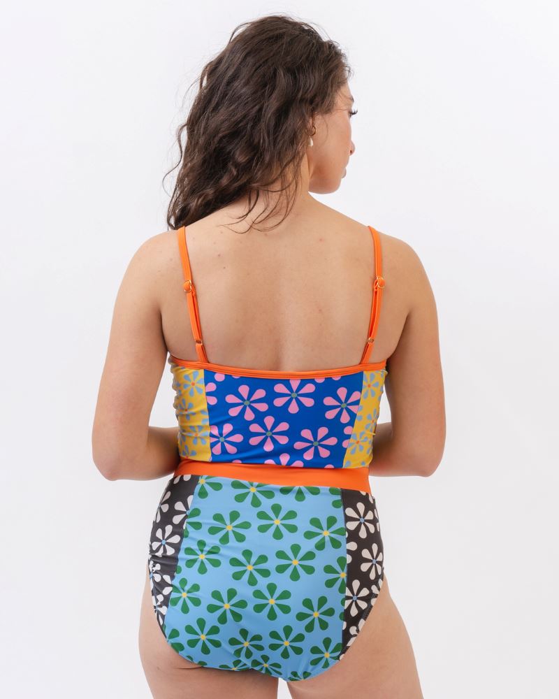 Photo of a woman wearing a multi-colored floral one-piece swimsuit- back angle