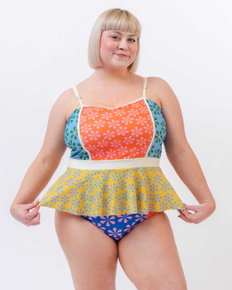 Photo of a woman wearing a multi-colored floral peplum swim top and a multi-colored floral swim bottom