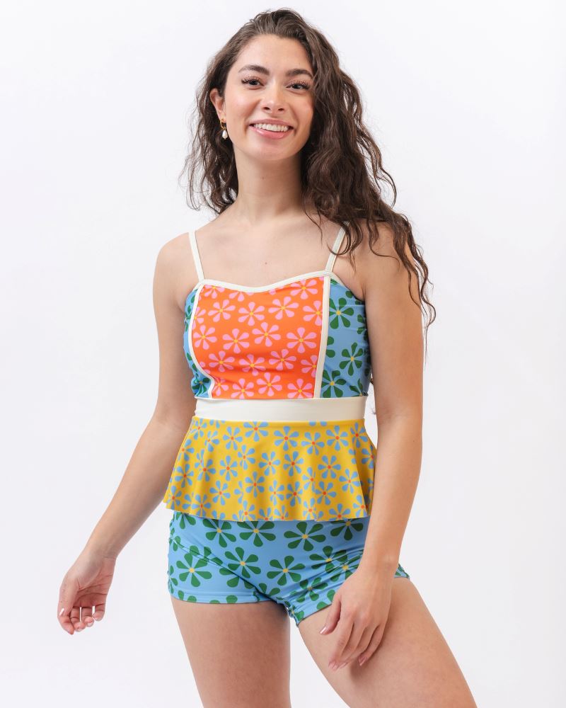 Photo of a woman wearing a multi-colored floral peplum swim top and a blue and green floral swim short bottom