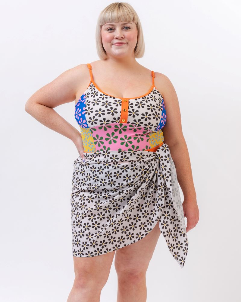 Photo of a woman wearing a black and white floral sarong and a multi colored floral one-piece swimsuit