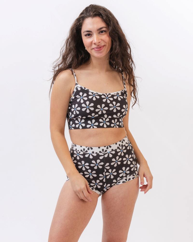 Photo of a woman wearing a black and white floral swim bralette and a black and white floral swim short bottom