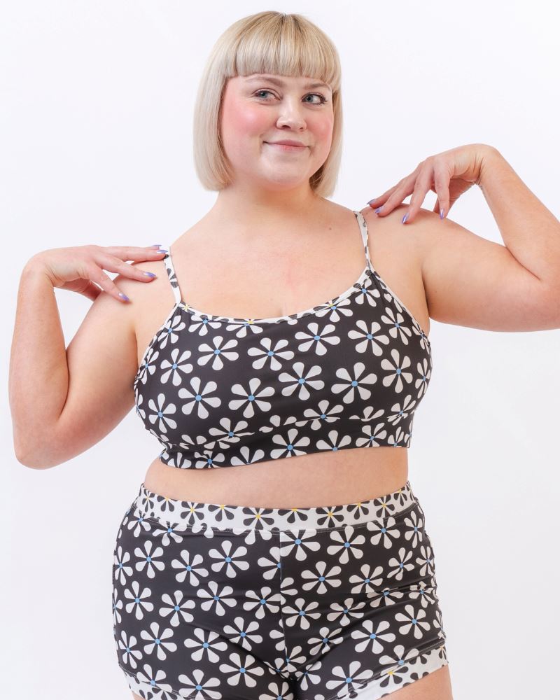Photo of a woman wearing a black and white floral swim bralette and a black and white floral swim short bottom