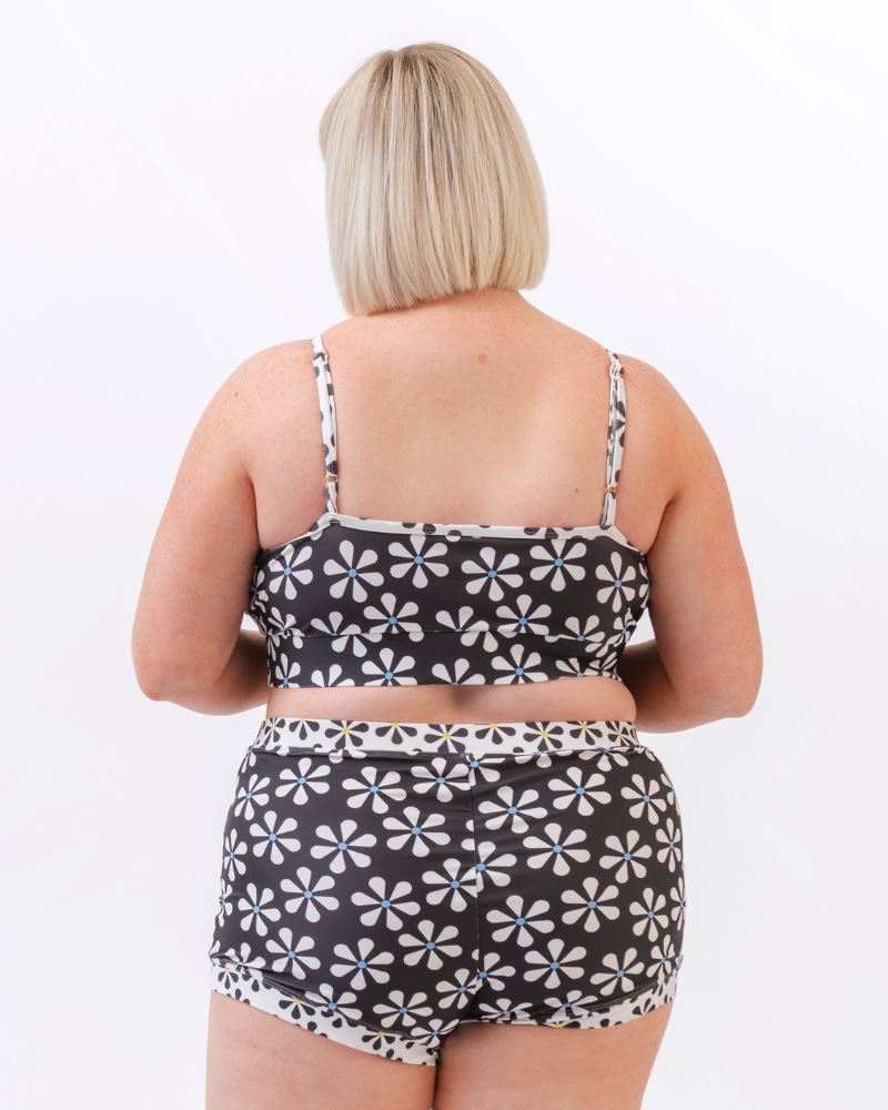 Photo of a woman wearing a black and white floral swim bralette and a black and white floral swim short bottom- back angle