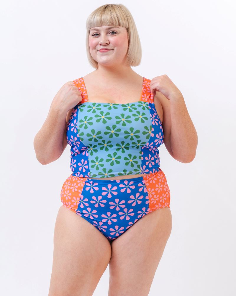 Photo of a woman wearing a multi-colored floral high-waist swim bottom and a multi-colored floral swim crop top