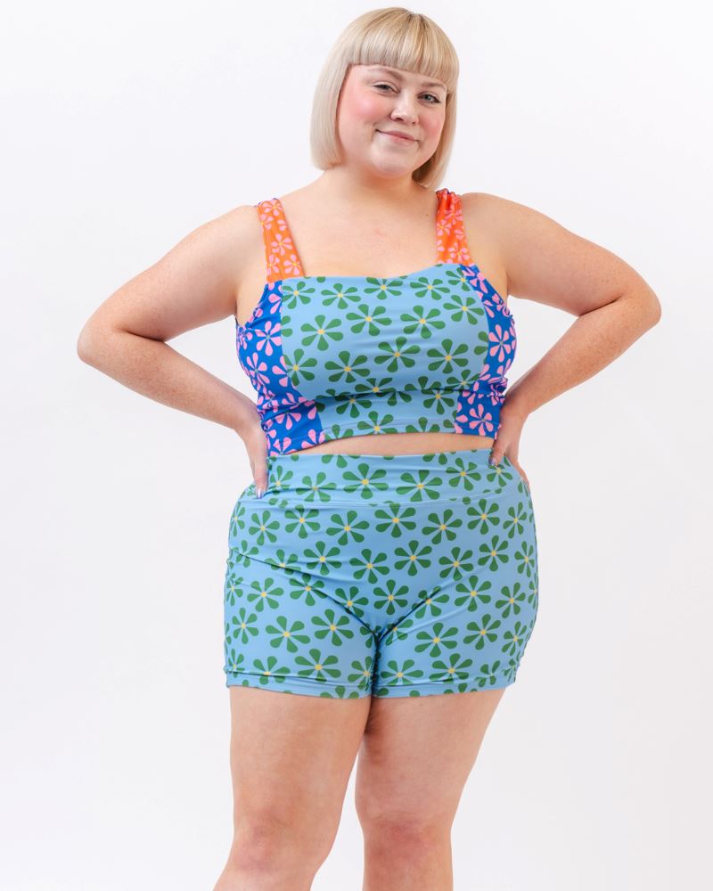 Photo of a woman wearing a blue and green floral swim short bottom and a multi colored floral swim crop top