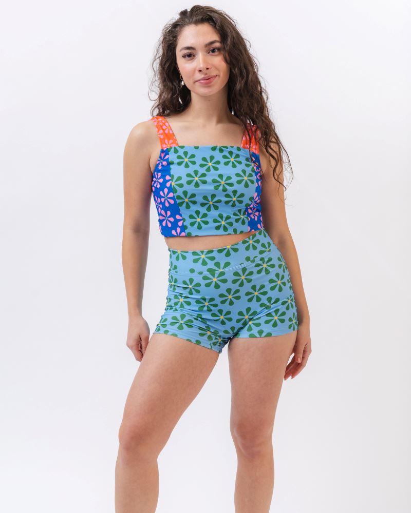Photo of a woman wearing a blue and green floral swim short bottom and a multi colored floral swim crop top