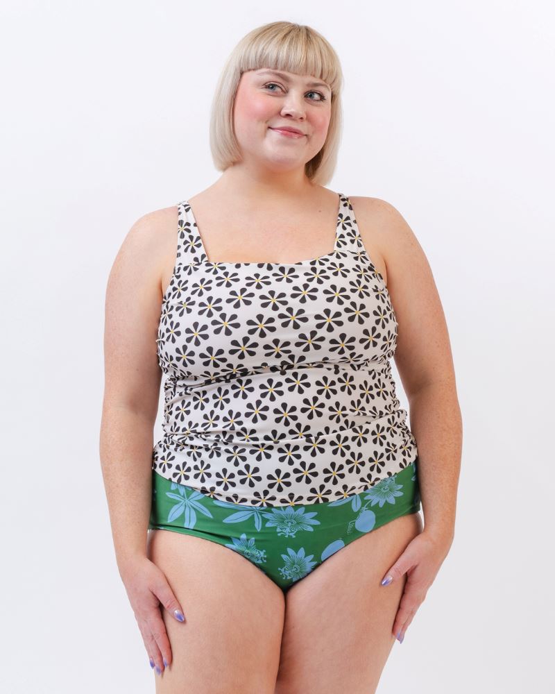 Photo of a woman wearing a black and white floral square neck swim top and a blue and green floral swim bottom