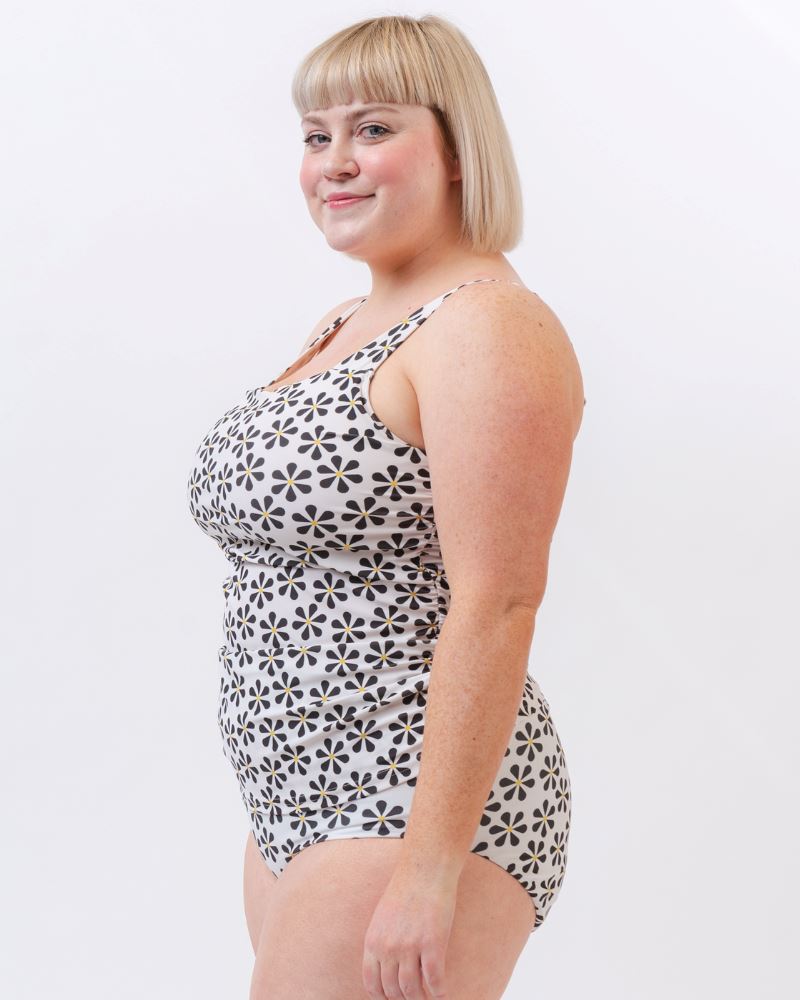 Photo of a woman wearing a black and white floral square neck swim top and a black and white floral swim bottom- side angle