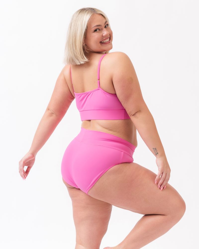 Photo of a woman wearing dark pink swim bralette and a dark pink swim bottom -side angle