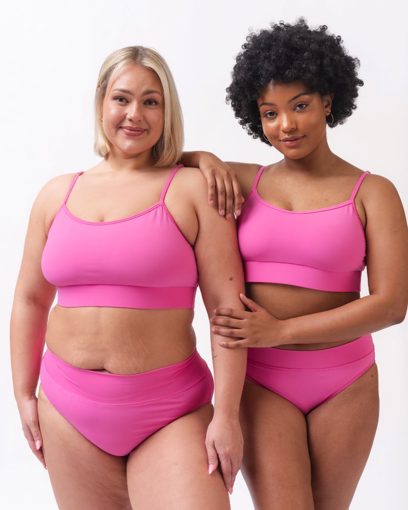 Photo of two women wearing dark pink swim bralettes and dark pink swim bottoms