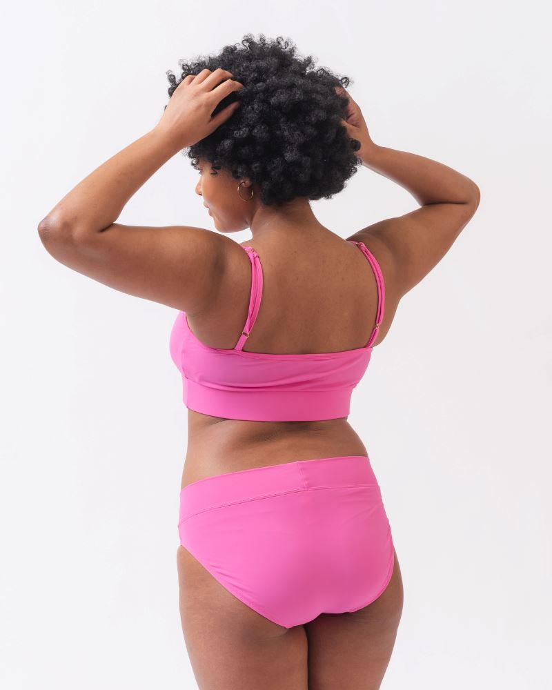 Photo of a woman wearing a dark pink swim top and dark pink classic swim bottoms -back angle