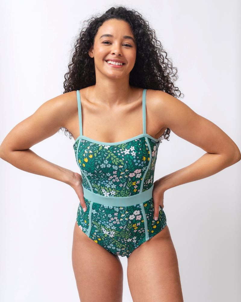 Photo of a woman wearing a dark green floral classic one-piece swimsuit