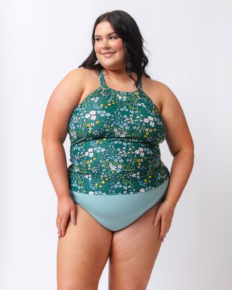 Photo of a woman wearing a dark green floral double-cinch tankini swim top and a light blue high waist swim bottom