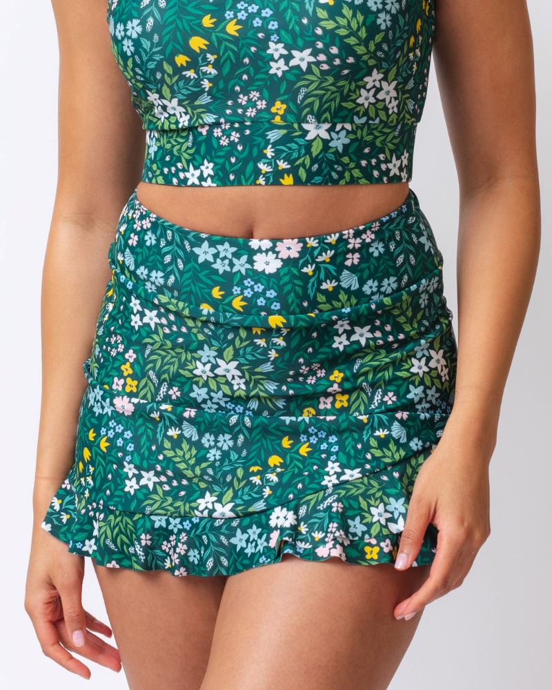 Close up photo of a woman wearing a dark green floral swim skirt