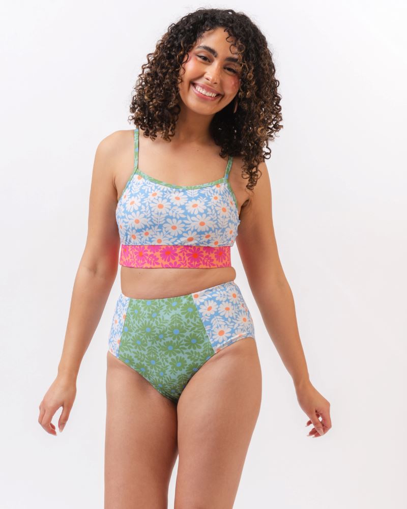 Photo of a woman wearing a blue and pink floral cropped swim top with blue and green floral high waist swim bottoms