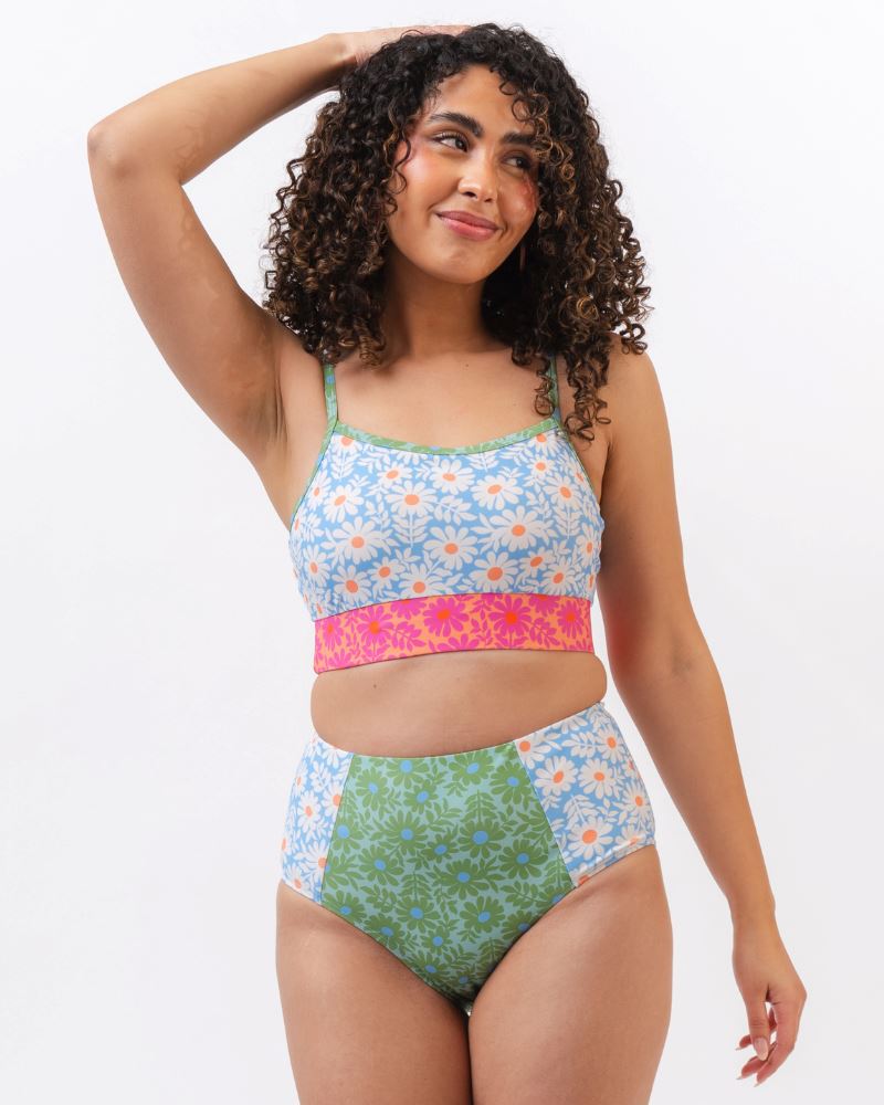 Photo of a woman wearing a blue and pink floral cropped swim top with blue and green floral high waist swim bottoms