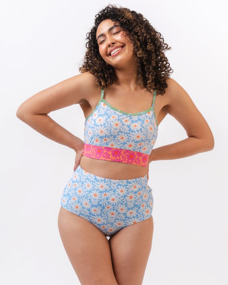 Photo of a woman wearing a blue and pink floral cropped swim top with blue floral high waist reversible swim bottoms