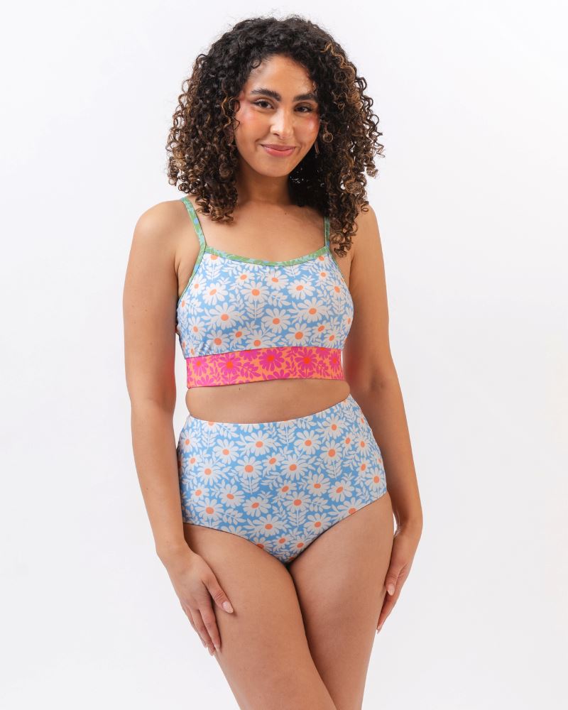 Photo of a woman wearing a blue and pink floral cropped swim top with blue floral high waist reversible swim bottoms