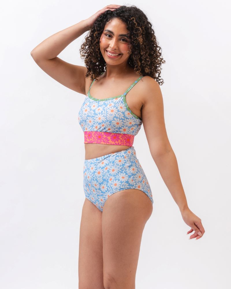 Photo of a woman from the side wearing a blue and pink floral cropped swim top with blue floral high waist reversible swim bottoms