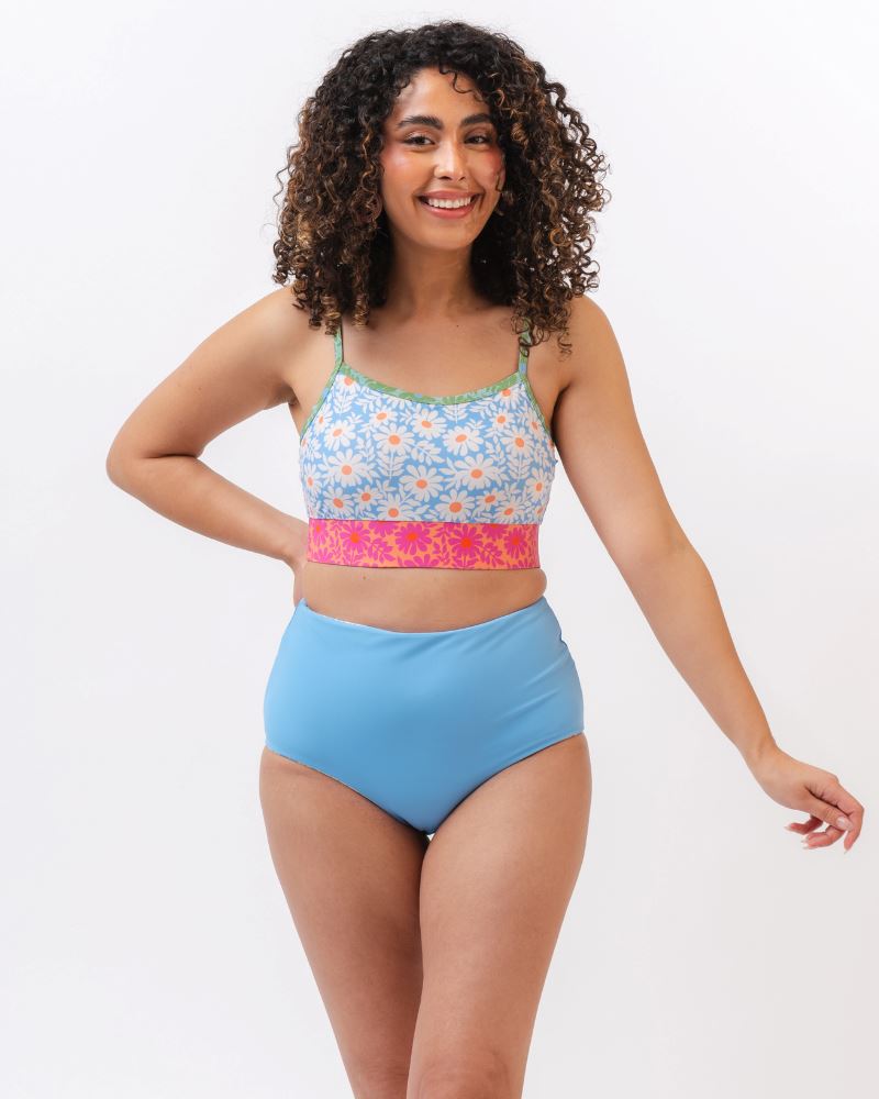 Photo of a woman wearing a blue and pink floral cropped swim top with blue high waist reversible swim bottoms