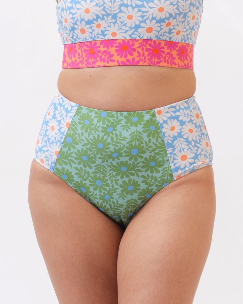 Close up photo of a woman wearing a blue and pink floral cropped swim top with blue and green floral high waist swim bottoms