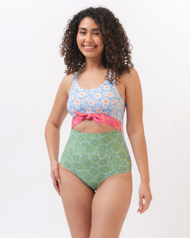 Photo of a woman wearing a blue and green floral knotted one piece swim suit