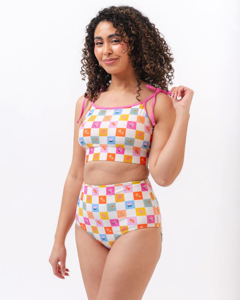 Photo of a woman wearing a multi colored checkered print cropped swim top with multi colored checkered print high waist swim bottoms