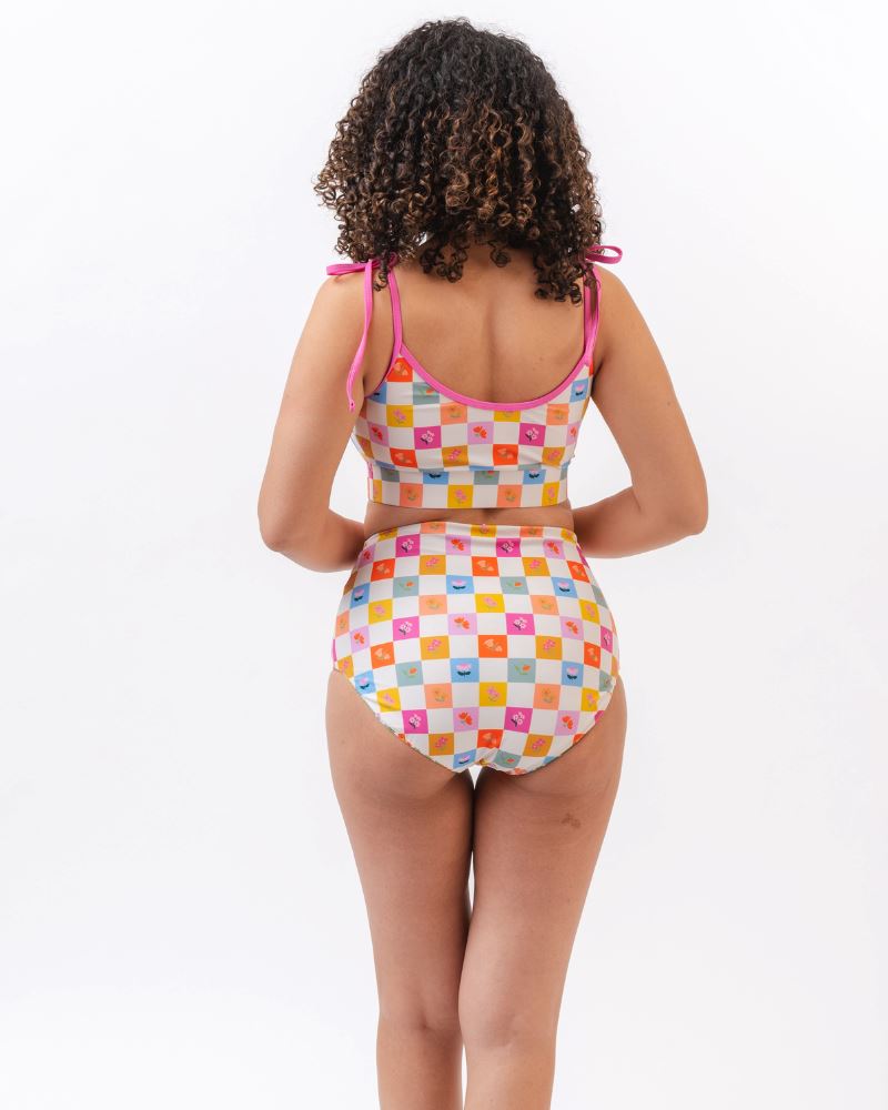 Photo of a woman with her back facing us  wearing a multi colored checkered print cropped swim top with multi colored checkered print high waist swim bottoms
