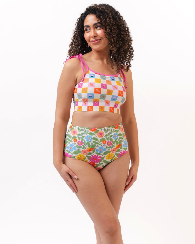 Photo of a woman wearing a multi colored checkered print cropped swim top with multi colored floral high waist swim bottoms