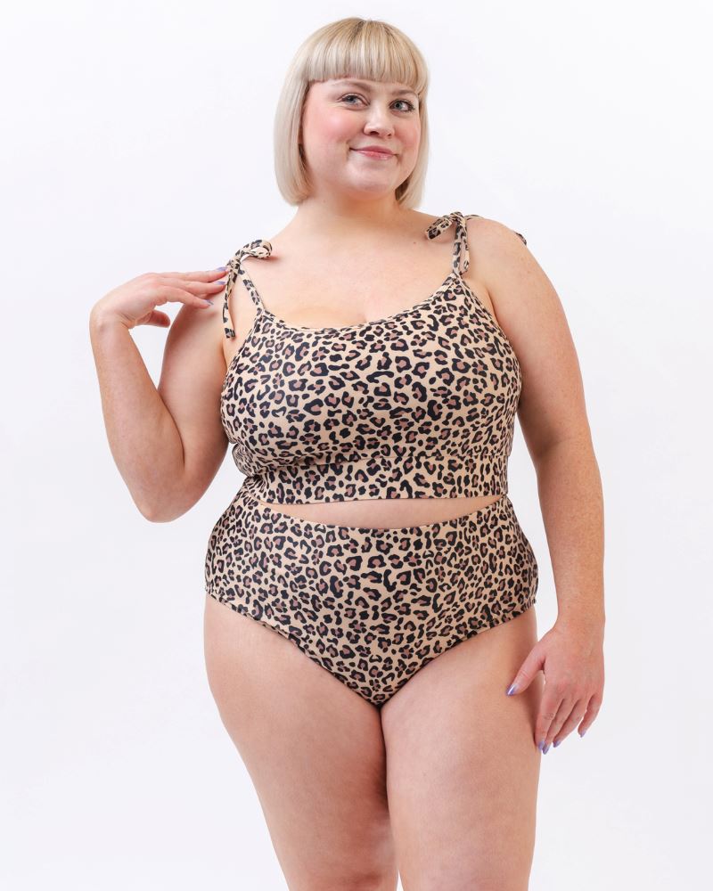 Photo of a woman wearing a leopard print high waist swim bottom and a leopard print shoulder-tie swim crop top